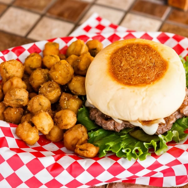Bull Chicks burger with melted cheese, lettuce, and fried mushrooms in a red and white checkered basket.